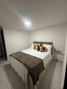 una camera da letto con un grande letto bianco con cuscini di Bangalô no condomínio Victory em Lucena-PB a Lucena