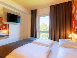 B&B Hotel Stuttgart-Bad Cannstatt في شتوتغارت: غرفه فندقيه بسرير ونافذه