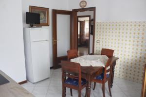 una sala da pranzo con tavolo, sedie e frigorifero di Moreno House - Appartamento due camere a Castagnole