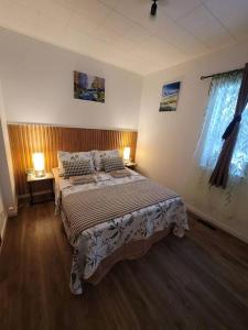 1 dormitorio con 1 cama con 2 lámparas y 2 ventanas en Warm cozy 1 bdrm close to Hwy, en Edmundston