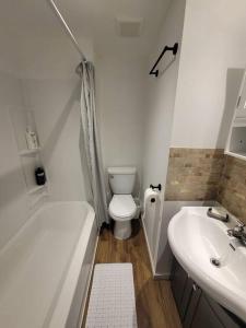 a white bathroom with a toilet and a sink at Warm cozy 1 bdrm close to Hwy in Edmundston