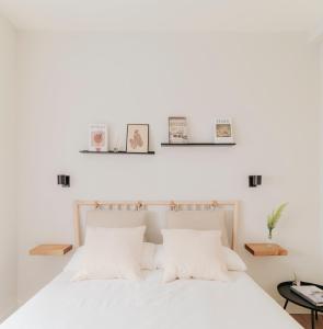 a bedroom with a white bed with three pictures on the wall at Apartamento de diseño en Pozuelo in Pozuelo de Alarcón