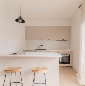 uma cozinha com armários brancos e dois bancos em Apartamento de diseño en Pozuelo em Pozuelo de Alarcón