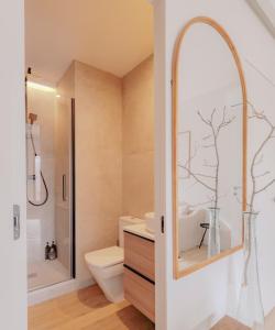 a bathroom with a toilet and a shower and a mirror at Apartamento de diseño en Pozuelo in Pozuelo de Alarcón