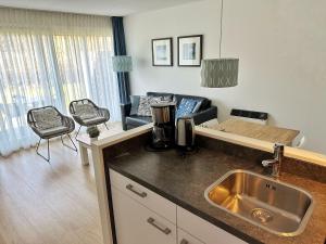 a kitchen with a sink and a living room at Kaap 10 in Hollum