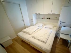 a small white room with a bed and a chair at Kaap 10 in Hollum +19 photos