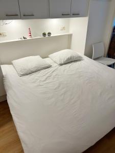 Una cama blanca con dos almohadas encima. en Kaap 10, en Hollum