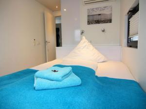 a bed with a blue blanket and two towels on it at Houseboat Floating House "Leni", Ribnitz-Damgarten in Ribnitz-Damgarten