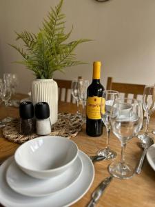 a table with a white plate and a bottle of wine at Stylish 3 Bed House Hitchin in Hitchin