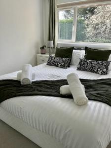 a large white bed with pillows and a window at Stylish 3 Bed House Hitchin in Hitchin