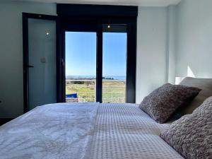 a bedroom with a bed with a large window at Blanca Mañana in Ribeira