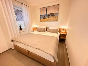 een slaapkamer met een bed en een raam met een vuurtoren bij Haus Hobbingshof Greetsiel in Greetsiel