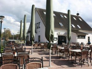 eine Gruppe von Tischen und Stühlen mit Sonnenschirmen vor einem Gebäude in der Unterkunft Holiday room Lenzer Hafen in Lenz