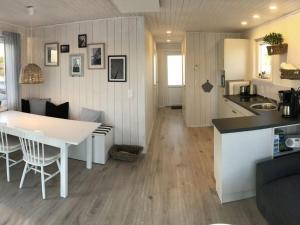 Il dispose d'une cuisine et d'un salon avec une table et des chaises blanches. dans l'établissement Houseboat NORDIC, à Großenbrode