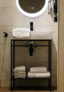 bagno con lavandino, specchio e asciugamani di Hotel Blink a Valkenburg