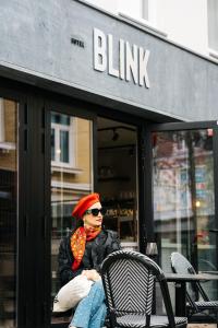 Una donna seduta su una sedia di fronte a un edificio di Hotel Blink a Valkenburg