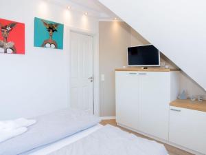 ヴァンガーオーゲにあるBoothäuser Living_art Wangeroogeの白いベッドルーム(ベッド1台、テレビ付)