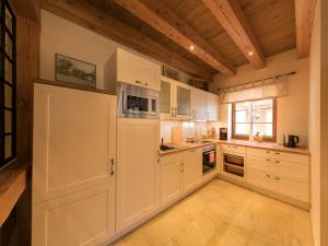 una cucina con armadi bianchi e soffitto in legno di Carl-Lambrecht-Chalet No 19 a Ilsenburg