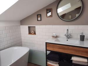 ein Badezimmer mit einer Badewanne, einem Waschbecken und einem Spiegel in der Unterkunft Holiday home Old Kate in Bosau