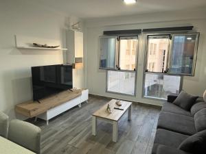 a living room with a couch and a flat screen tv at Acogedor apartamento con piscina yedae in Gáldar