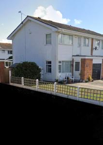 une maison blanche avec une clôture devant elle dans l'établissement Spacious three bedroom property in Penrhyn bay - sleeps 6, à Penrhyn Bay
