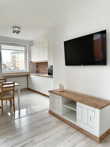 格但斯克的住宿－Przystanek Morena，厨房配有白色橱柜和壁挂式平面电视。