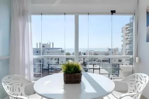 トレモリノスにあるPrecioso apartamento reformado con vistas directas al marの大きな窓のある客室で、白いテーブルと椅子が備わります。