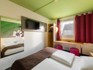 ヘルネにあるB&B Hotel Bochum-Herneのベッド2台とテレビが備わるホテルルームです。