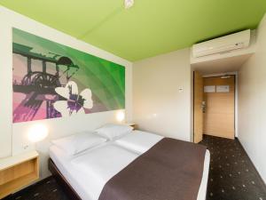 ヘルネにあるB&B Hotel Bochum-Herneのベッドルーム1室(壁に絵画が描かれたベッド1台付)