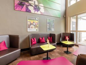 a waiting room with couches and tables and pink pillows at B&B Hotel Bochum-Herne in Herne
