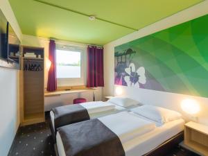 a bedroom with two beds and a green wall at B&B Hotel Bochum-Herne in Herne