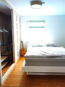 une chambre avec un lit blanc et une guitare dans l'établissement Ruhrpott-Paradies, à Duisbourg 5 autres photos