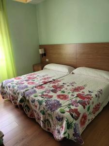 a bedroom with a bed with a floral quilt on it at Pensión O Regato in Redondela
