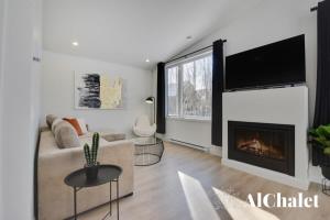 a living room with a couch and a fireplace at Achille - Boisé avec spa et sauna in Pont-Rouge