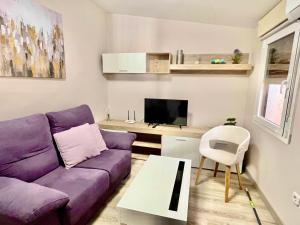 un soggiorno con divano viola e TV di Apartamento la Soledad, junto al Alcázar a Toledo