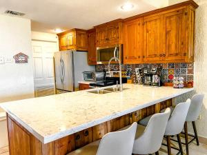 a kitchen with wooden cabinets and a marble counter top at Princesa de Penasco Condo C101 Sandy Beach Puerto Penasco in Puerto Peñasco