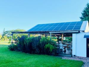 a pavilion with a solar array on it in a garden at Bella Manga Country Escape in Plettenberg Bay