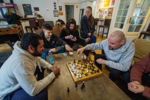 Un groupe de gens assis autour d'une table jouant aux échecs dans l'établissement Imaginary Hostel, à Tallinn