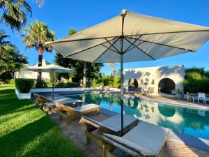 uma piscina com um guarda-sol e cadeiras e uma mesa em Bella Manga Country Escape em Plettenberg Bay