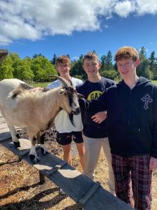 grupa chłopców stojących obok kozy w obiekcie Bella Manga Country Escape w mieście Plettenberg Bay