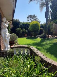 a garden with a statue of a woman and a pond at The Cottage at 19 in Kempton Park
