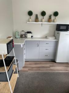 a kitchen with white cabinets and a white refrigerator at Modern studio apartment in Motueka
