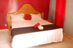 a bedroom with a large white bed with a red wall at Melia's hotel in Sali Nianiaral
