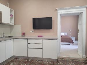 uma cozinha com armários brancos e uma televisão na parede em Domo Azuni em Sassari