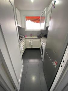 una piccola cucina con armadi bianchi e una finestra di 2 Chambres - 6pers - 10 min gare - proche Paris - lac d'Enghien - casino à proximité a Épinay-sur-Seine