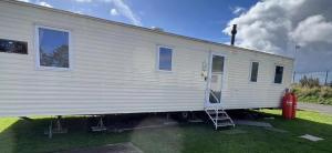 a white train car with a ladder next to a fire hydrant at St Marys Light house, Caravan Rentals in Whitley Bay