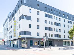 un bâtiment blanc au coin d'une rue dans l'établissement B&B Hotel Ludwigshafen, à Ludwigshafen