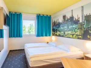 Schlafzimmer mit einem Bett mit blauen Vorhängen in der Unterkunft B&B Hotel Ludwigshafen in Ludwigshafen am Rhein