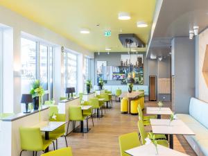 a restaurant with tables and yellow chairs at B&B Hotel Ludwigshafen in Ludwigshafen am Rhein