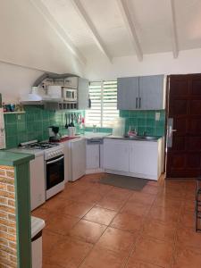 een keuken met witte kasten en groene tegels bij Chez LULU in Les Abymes